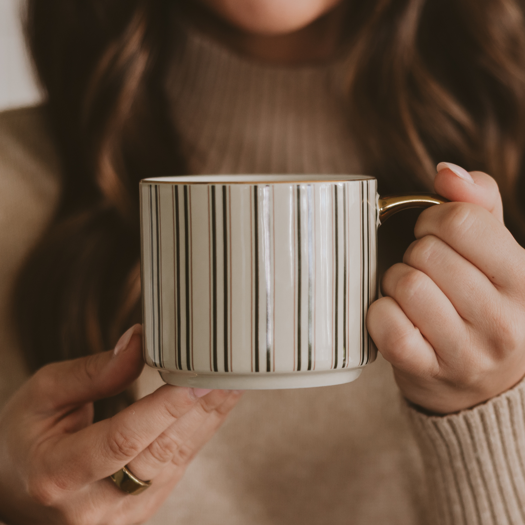 Blyskt Person holding a striped mug with a neutral background
