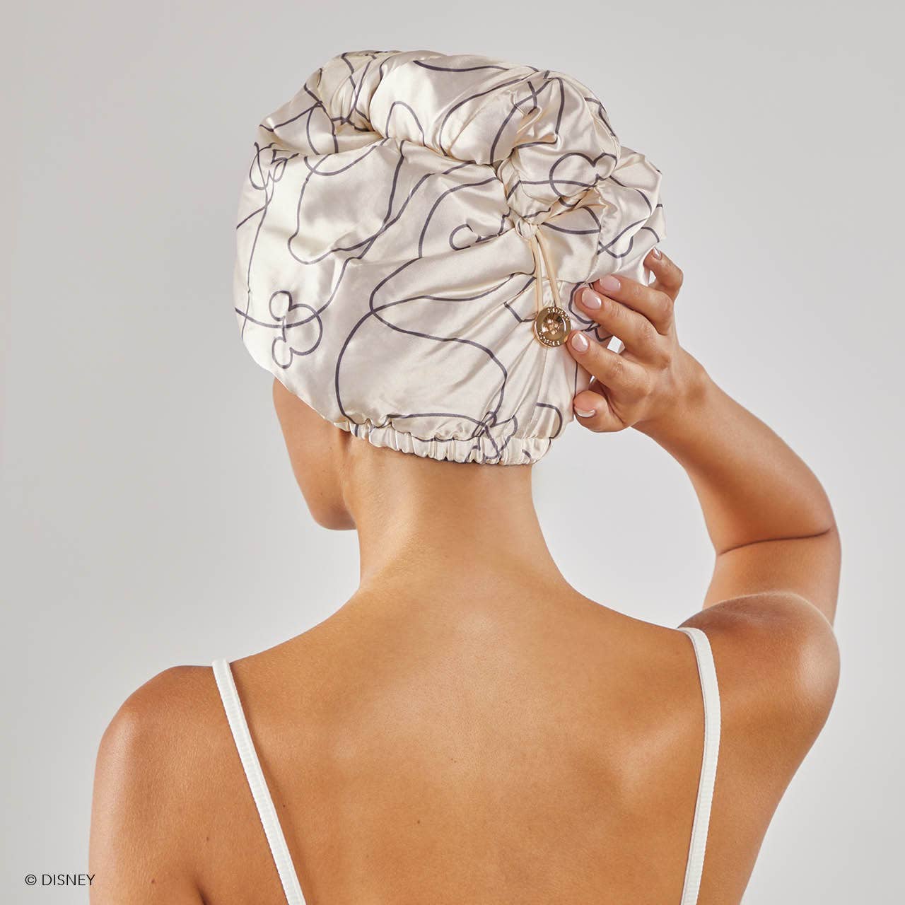 Blyskt  Person wearing a satin bonnet with floral patterns on a plain background