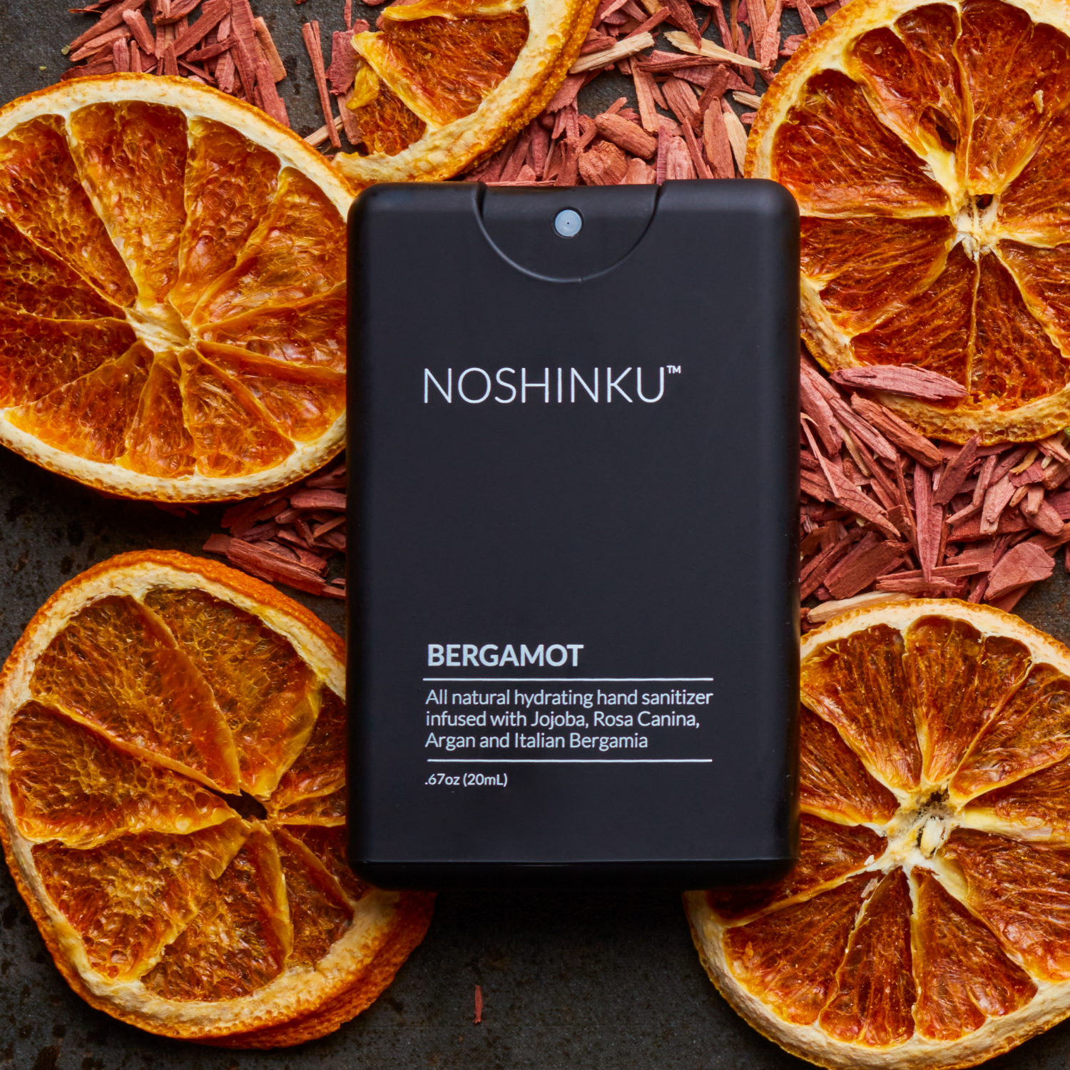 Noshinku Bergamot hand sanitizer bottle surrounded by dried orange slices and red herbs