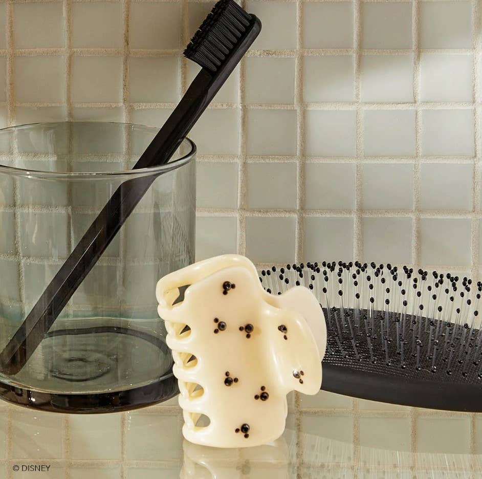 Blyskt Black toothbrush, white soap, and black comb on a tiled bathroom counter.