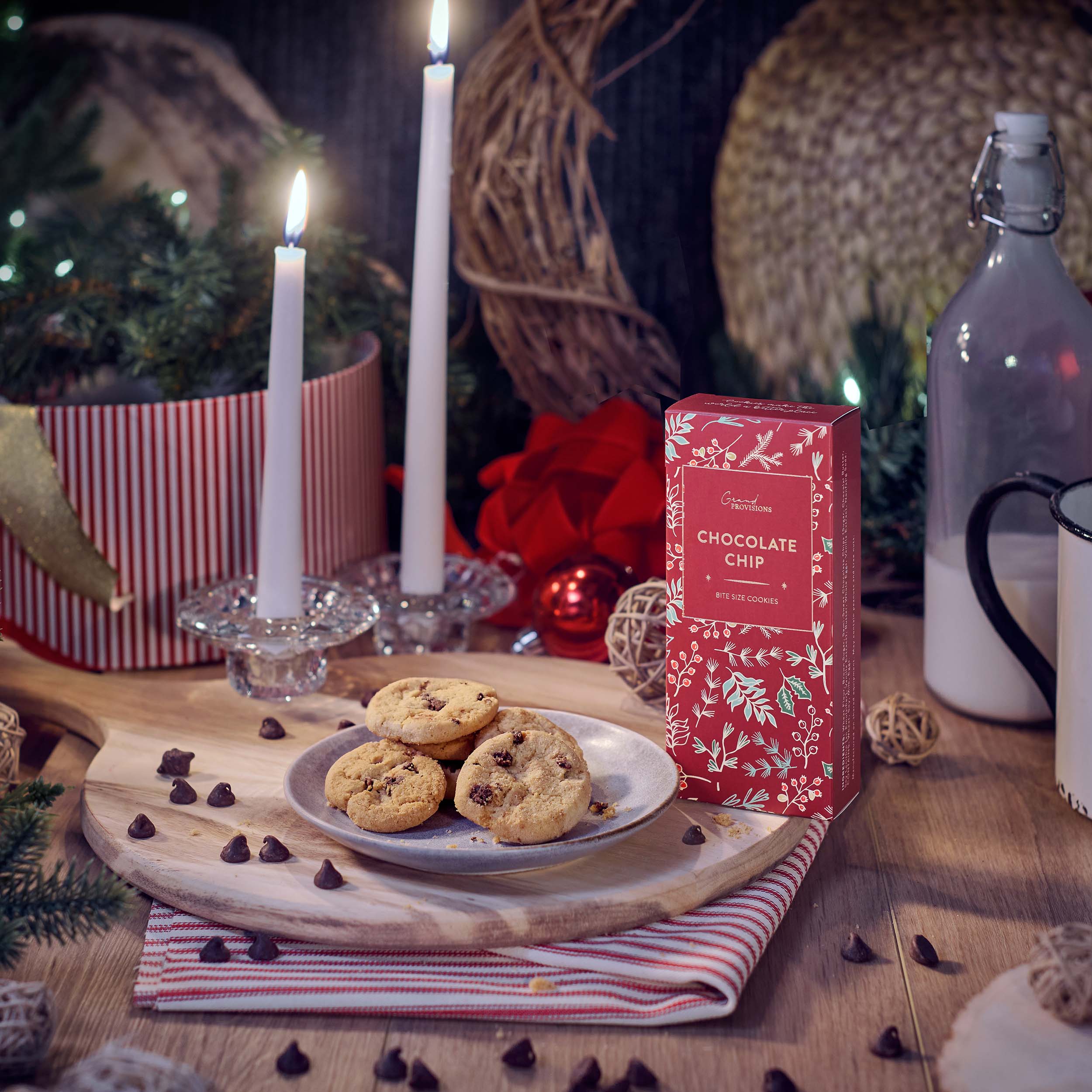 Blyskt Plate of cookies with a box of chocolate chip cookies on a festive table setting with candles and decorations.