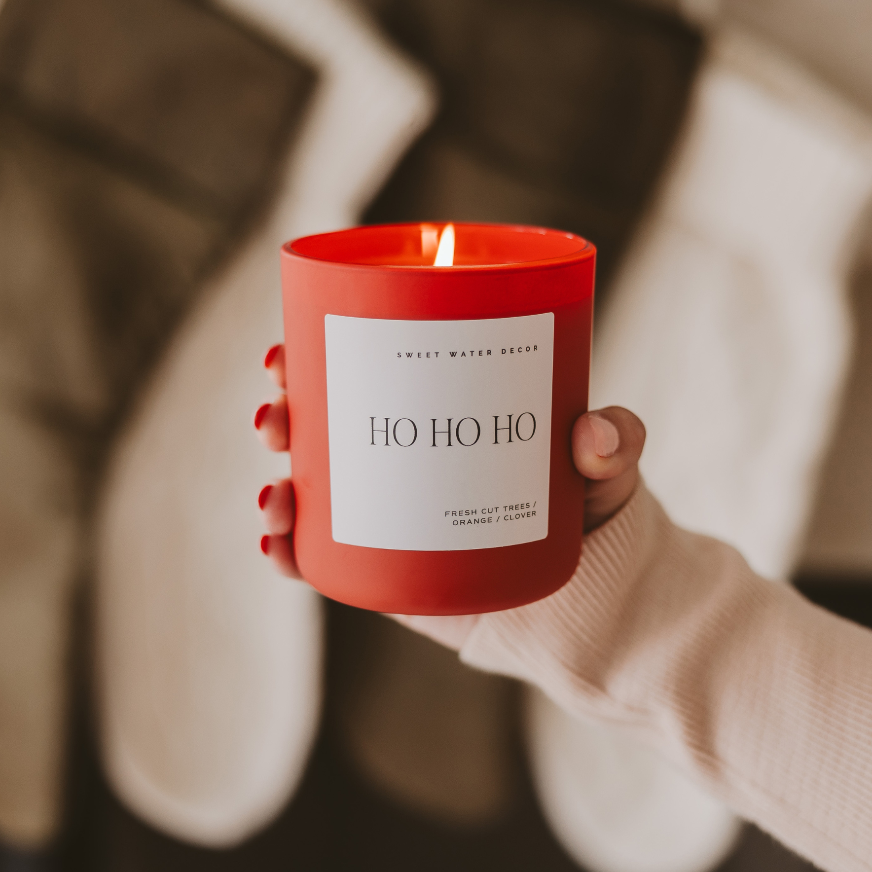 Blyskt Red candle labeled 'HO HO HO' held by a person wearing a beige sweater.