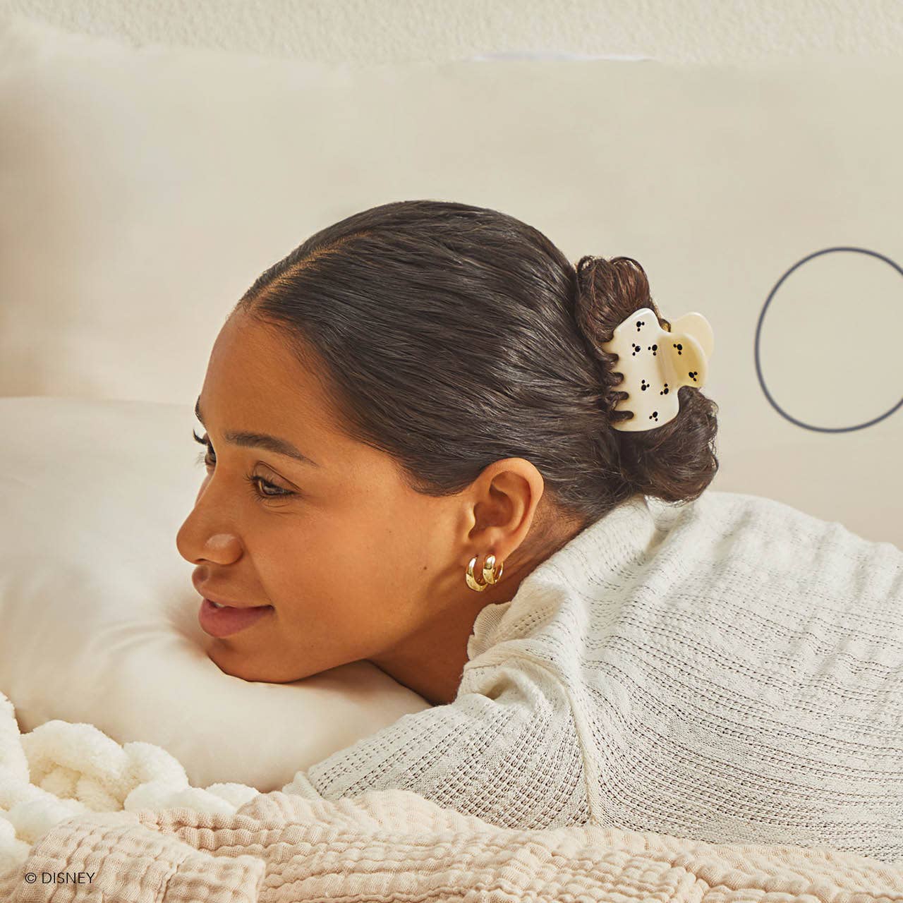 Blyskt Woman with a flower in her hair, wearing a white sweater, sitting on a couch.