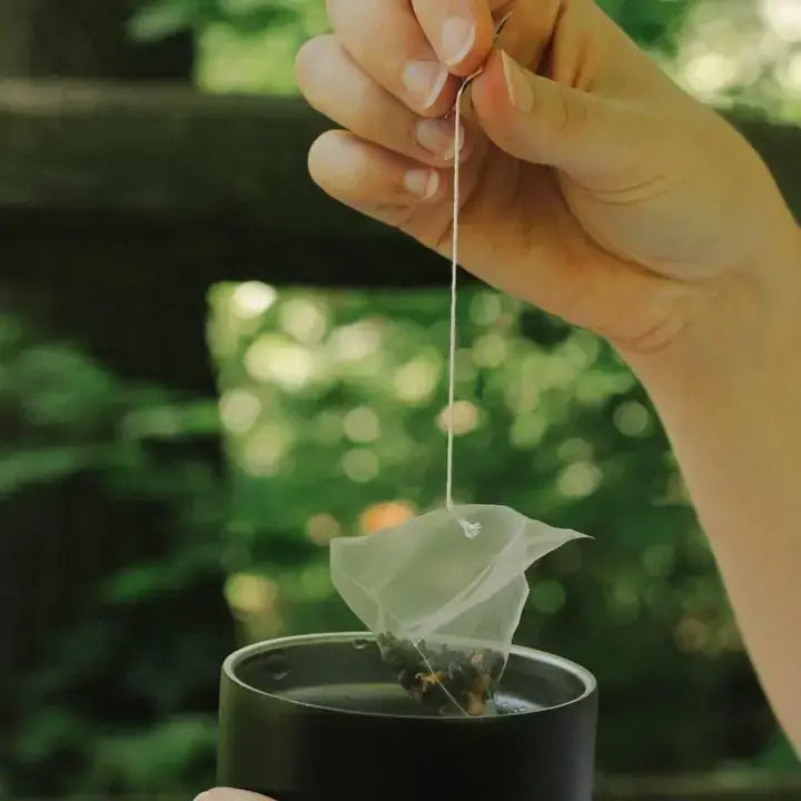 Hand dipping tea bag into black cup outdoors, highlighting calm Orlando gifting by Blyskt