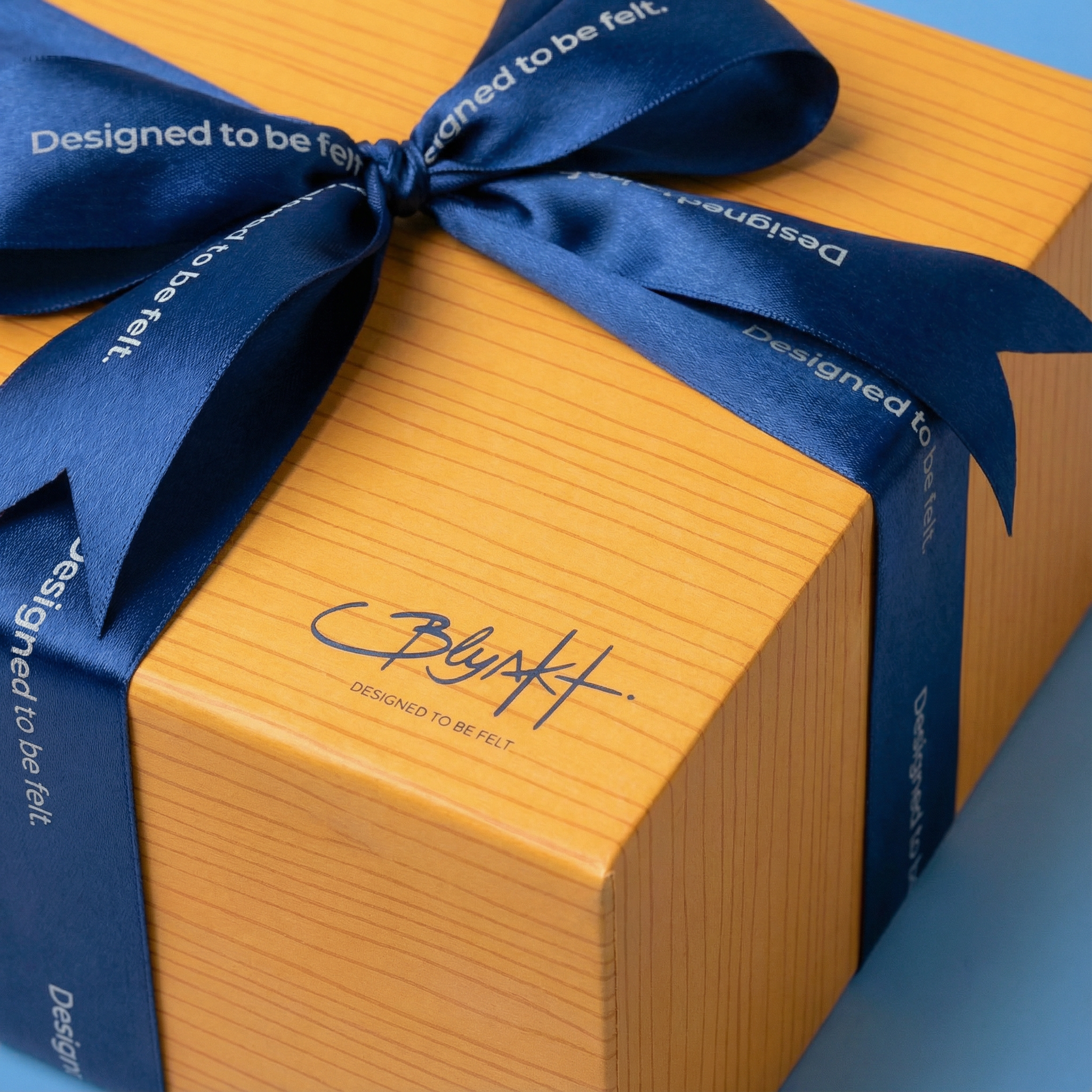 Blyskt Orange gift box with a blue ribbon and 'blyskt' branding on a light blue background